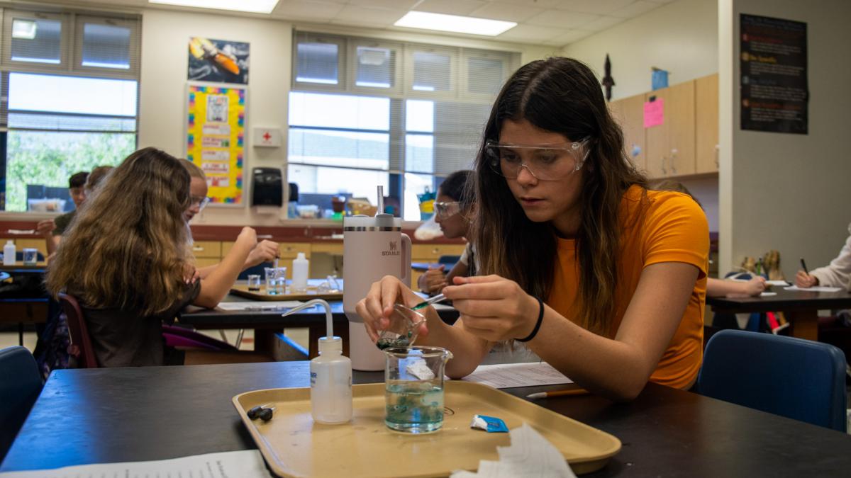 Middle school student in classroom performing a science experiment