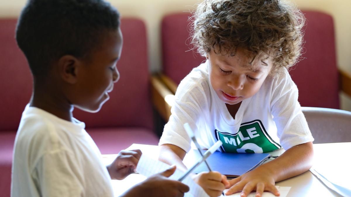 Two children writing on paper