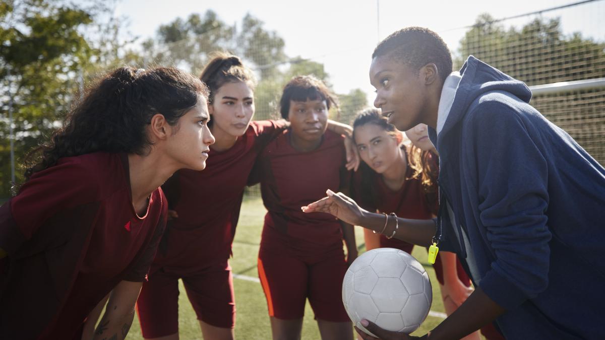 Coach talking to athletes on the field