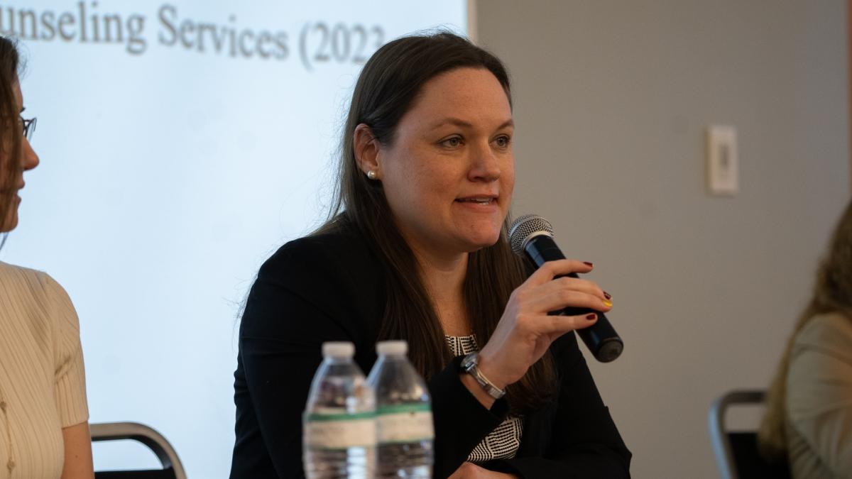 Woman holding a microphone speaking in a panel discussion