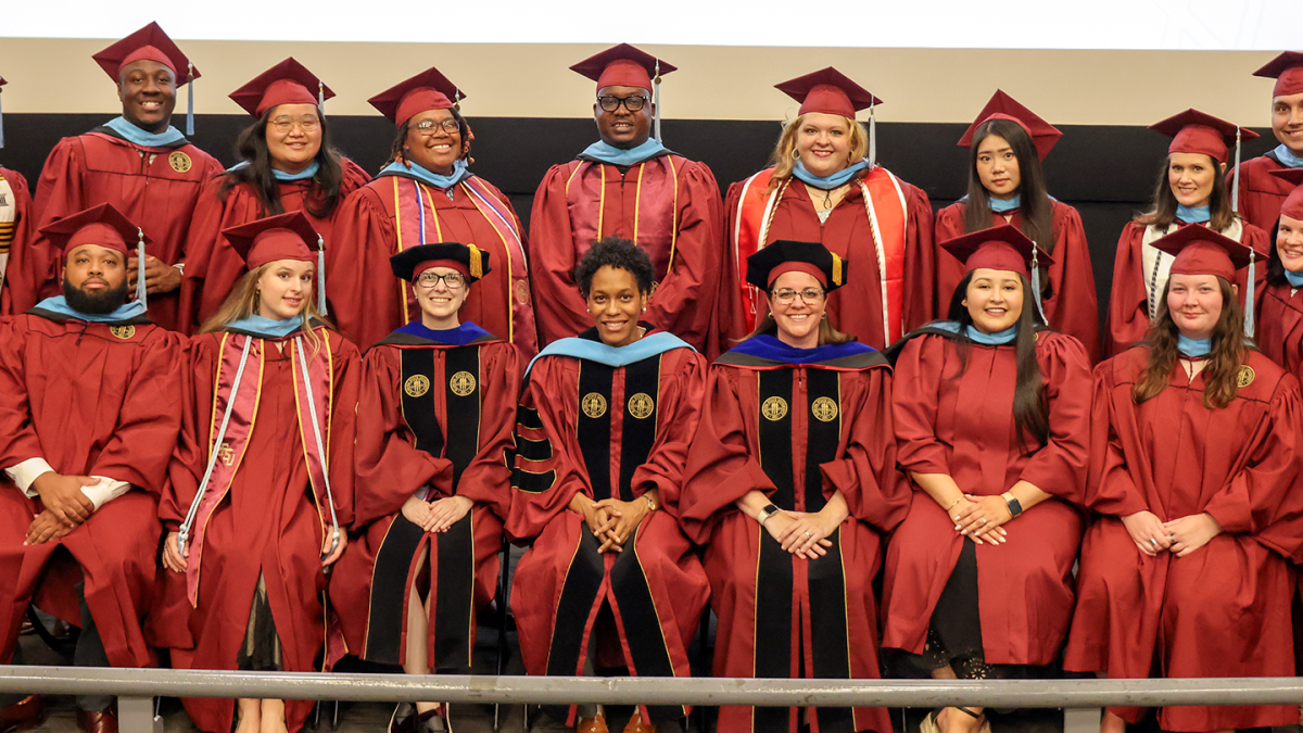 Doctoral and master's graduates gather for a group photo in their graduation regalia