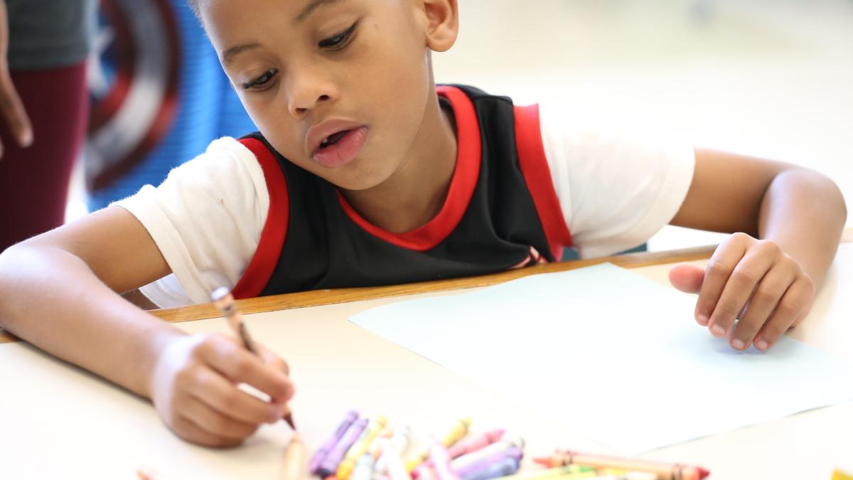 Child is drawing with crayons