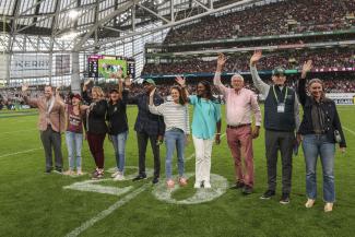 Group of teachers standing in the middle of a football stadium, waving