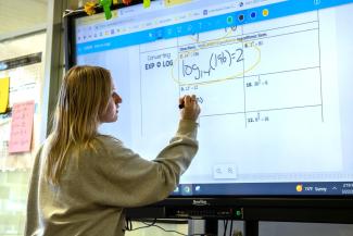 Girl writing math equations on a smart board