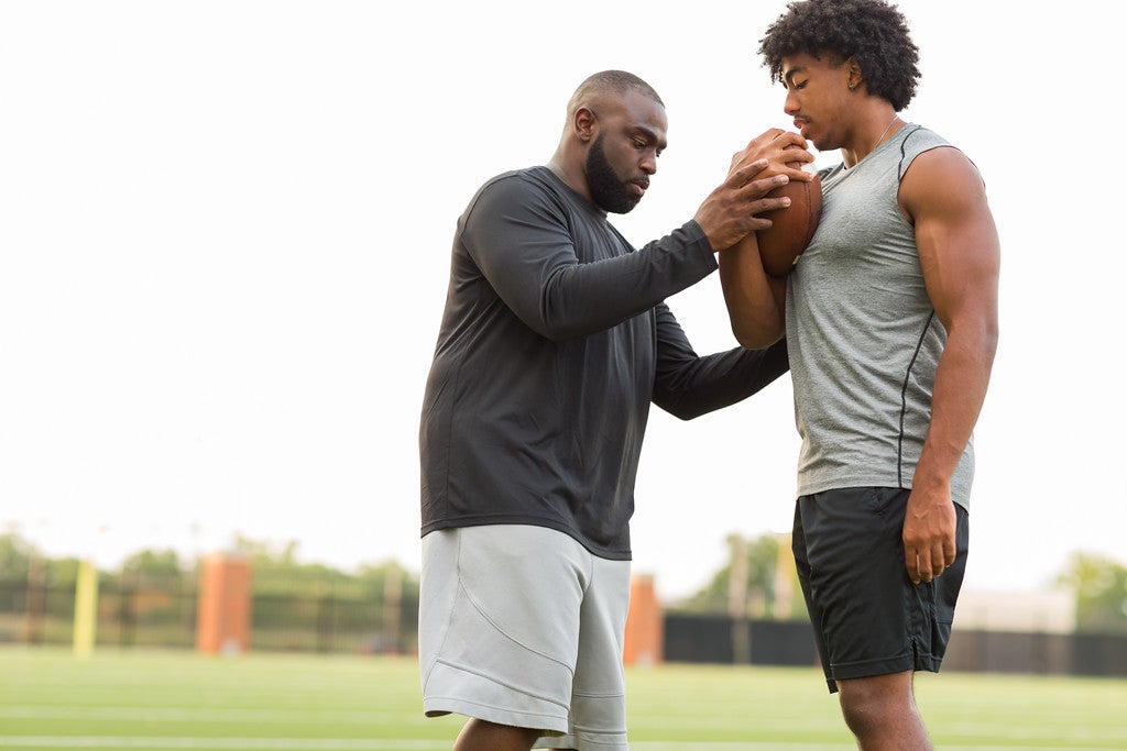 Coach teaching football athlete